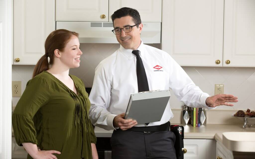 Orkin pest control technician goes over service with a customer in their kitchen