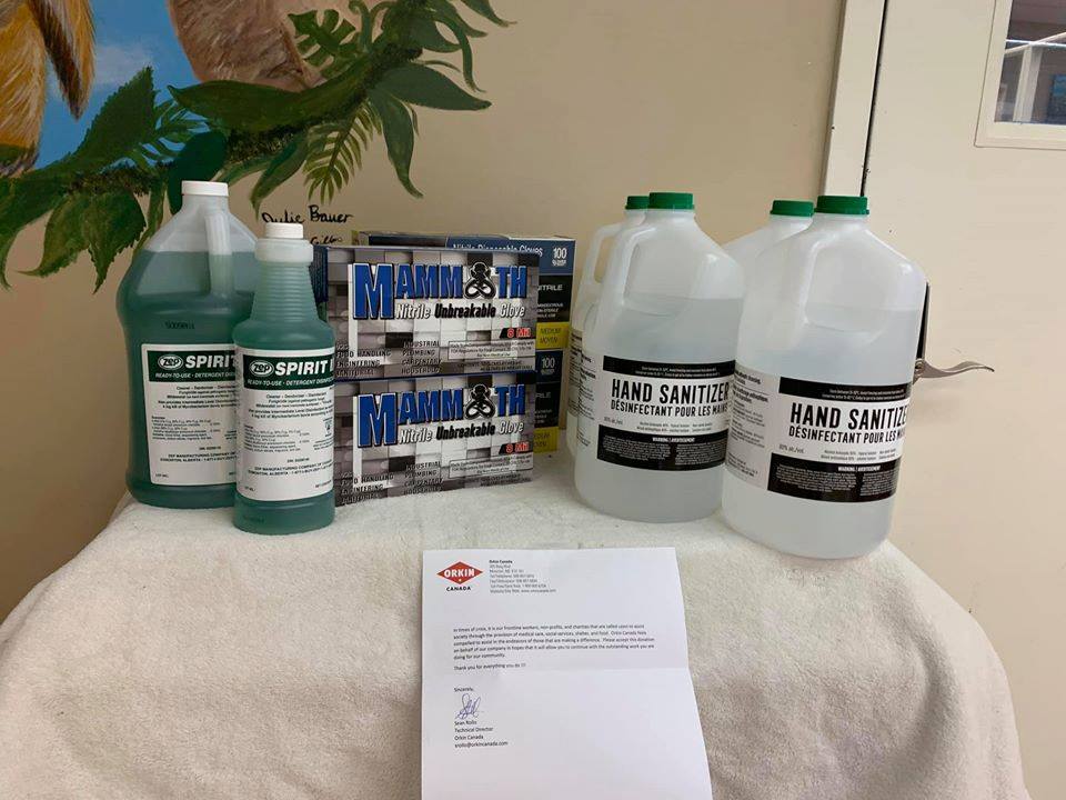 Donated disinfection supplies like gloves and sanitizer on a table with a thank you letter